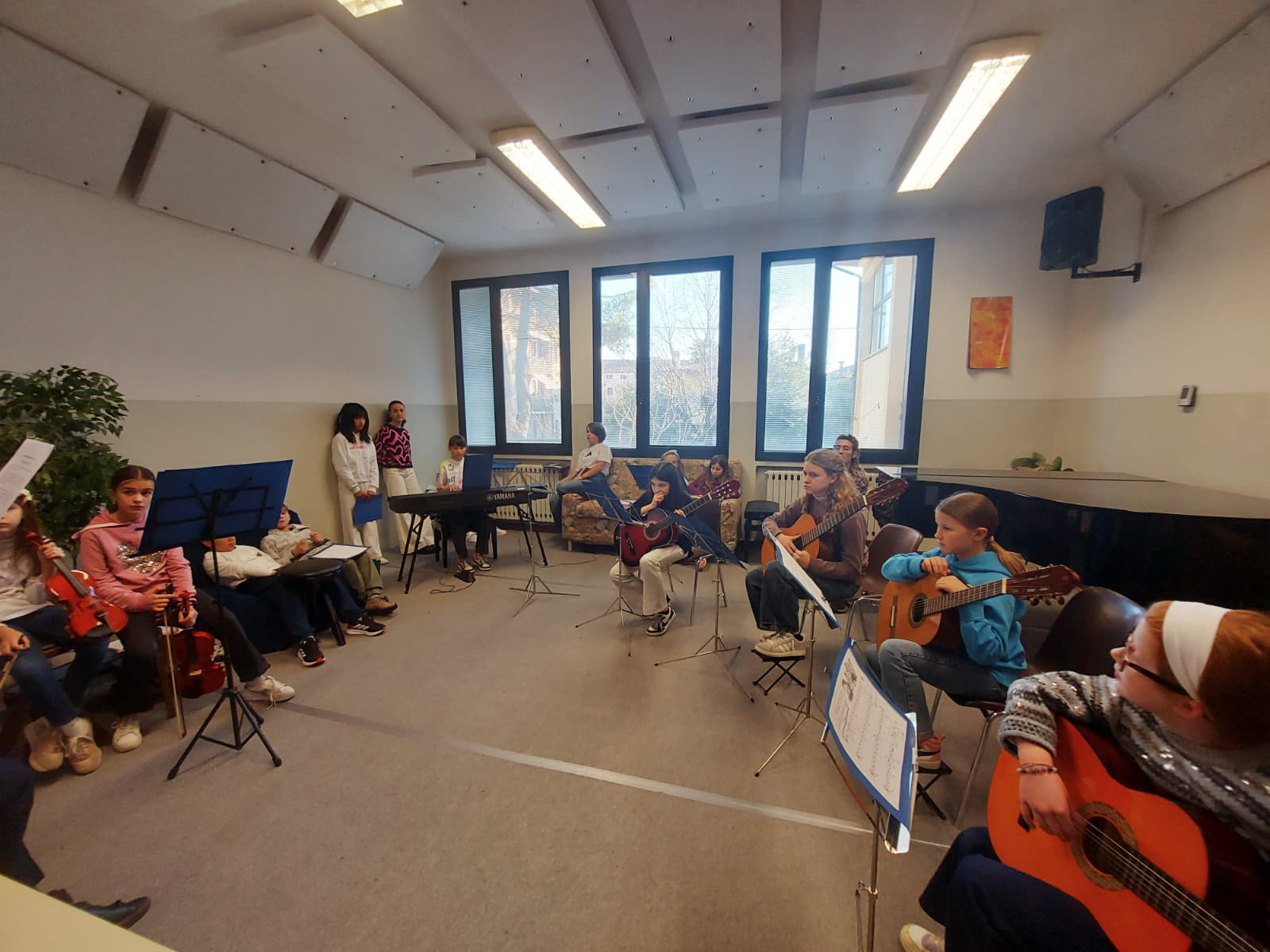 Allievi di chitarra, violino e tastiera che suonano insieme in aula